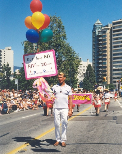 Bradford McIntyre, HIV+ since 1984, marches in the Vancouver PRIDE Parade 2004, holding his homemade sign: OUT ABOUT HIV - HIV+ FOR 20 YEARS - www.PositivelyPositive.ca.