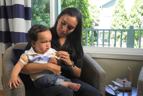 At their home, Tara Hatchie collects a nasal swab from her young son for a respiratory virus test. Photo Credit: Richard Marshall