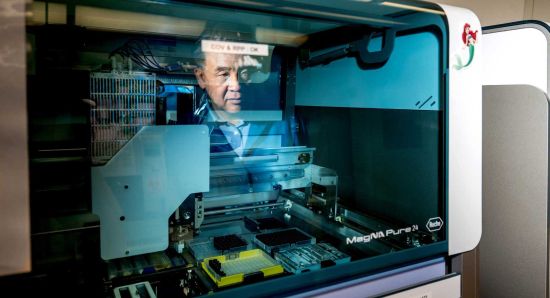 UCSF infectious diseases physician and microbiologist Charles Chiu, MD, PhD, watches as a robot extracts DNA from a sample. Photo by Noah Berger