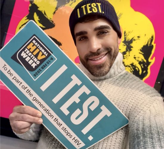 Dr. Ranj holds an 'I Test' sign for National HIV Testing Week.