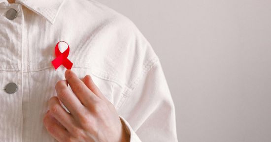 Person wearing jacket with s red ribbon to commemorate World AIDS Day