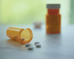 Two bottles of aspirin, one lying on its side with pills streaming out.