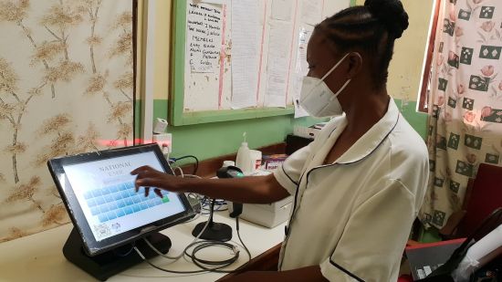 Health care worker in mask stands at tablet with electronic medical record system