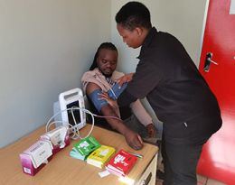 A person has his blood pressure monitored by a healcare worker in a medical setting in Uganda.